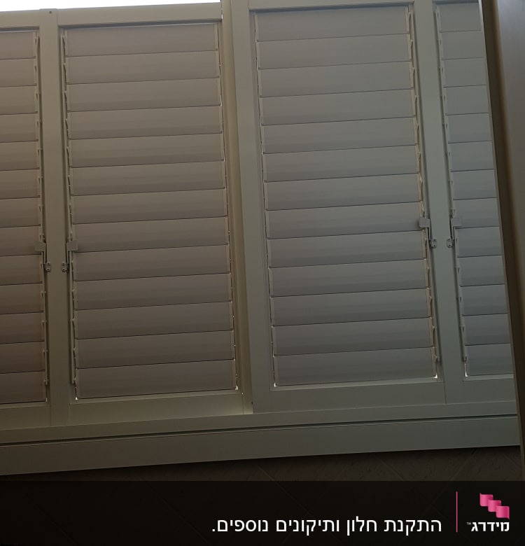 תריסי אלומיניום לבנים על חלון גדול